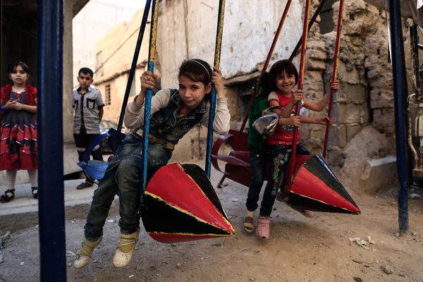 Syrian children play on swings, made from the remnants of exploded rockets in the rebel-held town of Douma, on the eastern edges of the capital Damascus, on Wednesday,  on the third day of Eid Al Adha holiday (AFP photo)